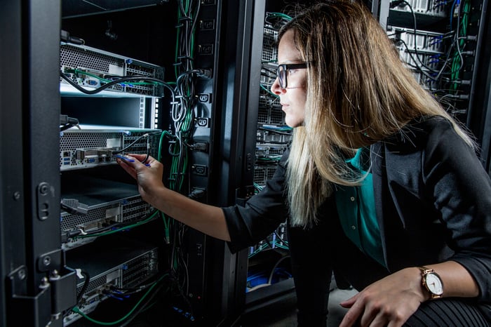 A technician is checking the wiring and powering up a data center server tower. 